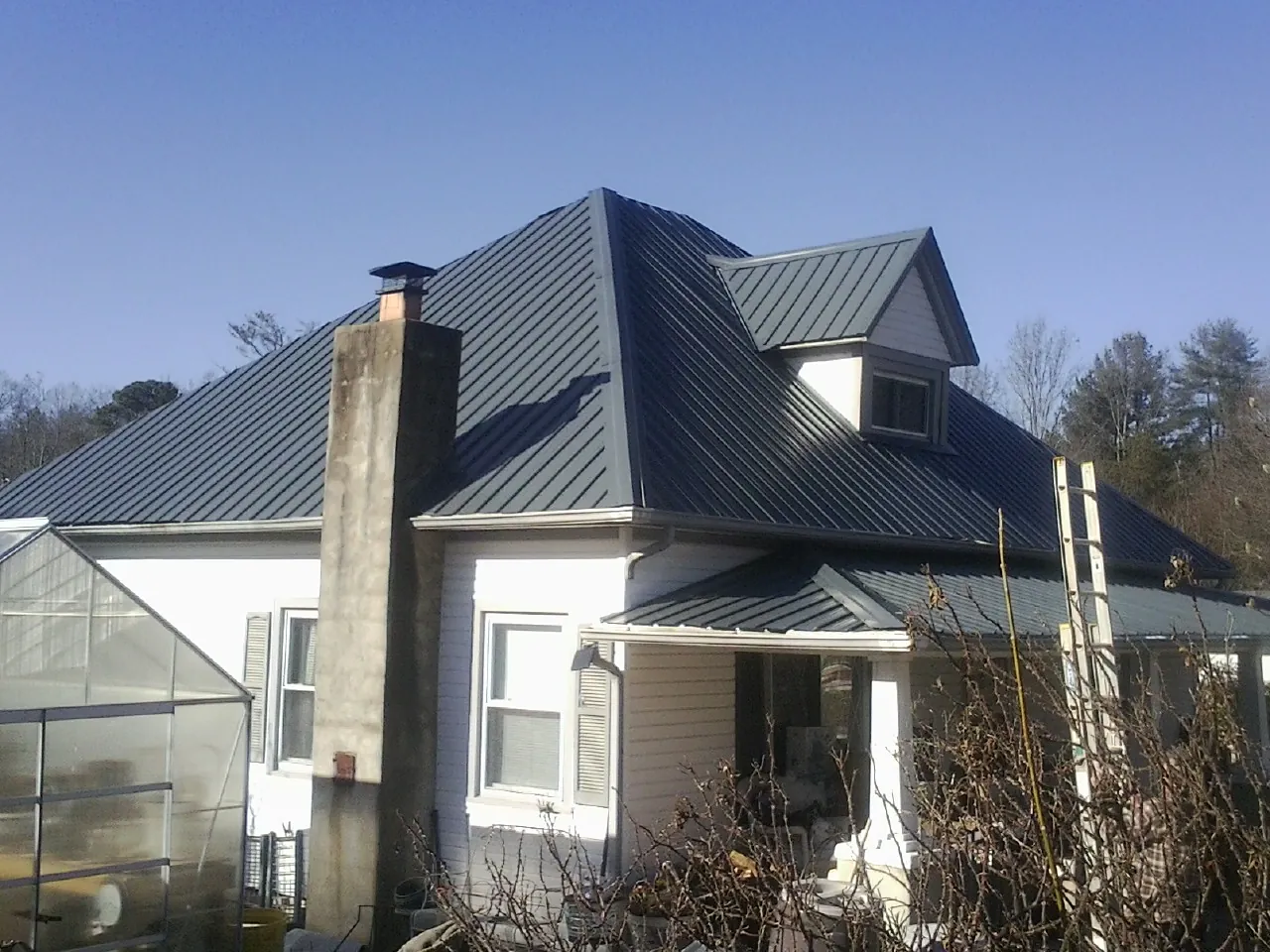 Dark blue standing seam metal roof on a white farmhouse with dormer — Slate & Tile Roof Repair by Roofing Brothers in Arock