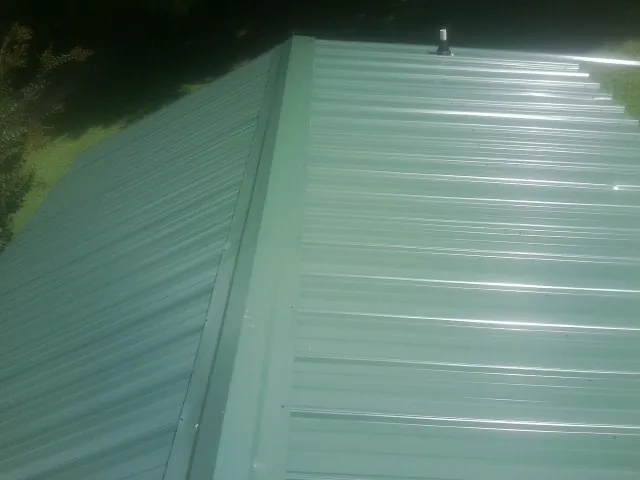 New green metal panels meeting at the ridge of a roof — Flat Roof Repair work by our crew in Arock
