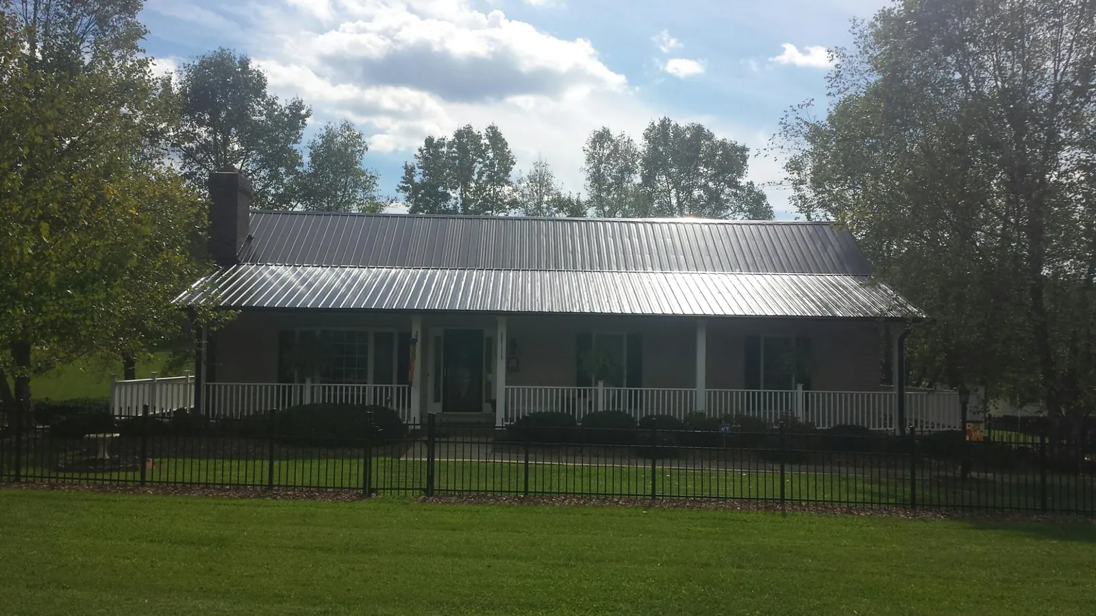 Gray metal roof on a brick ranch with a full width front porch — Gutter Guard Installation work by our crew in Arock